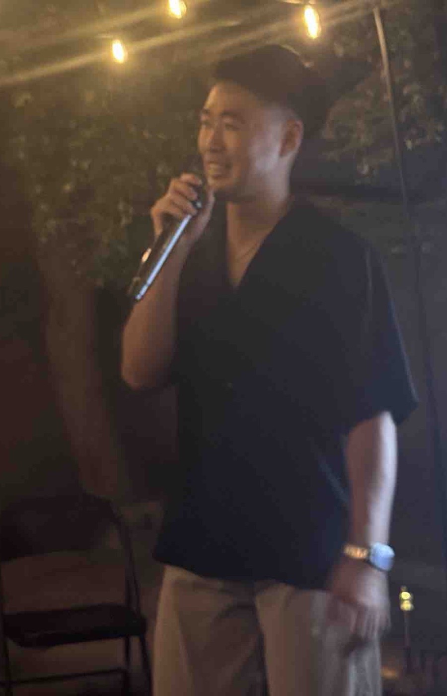 A founder answering a question into a microphone at the Founder Dinner, lit by string lights
