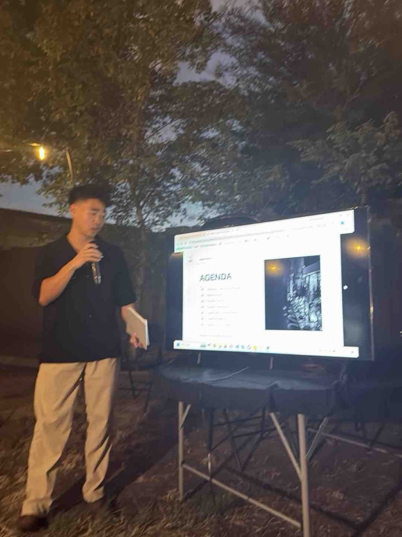 A founder presenting beside a screen in the garden at the Founder Dinner