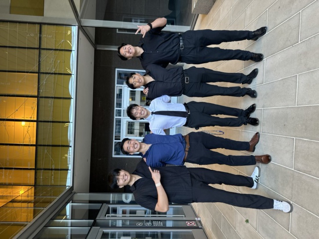 Five builders arm in arm outside a glass building