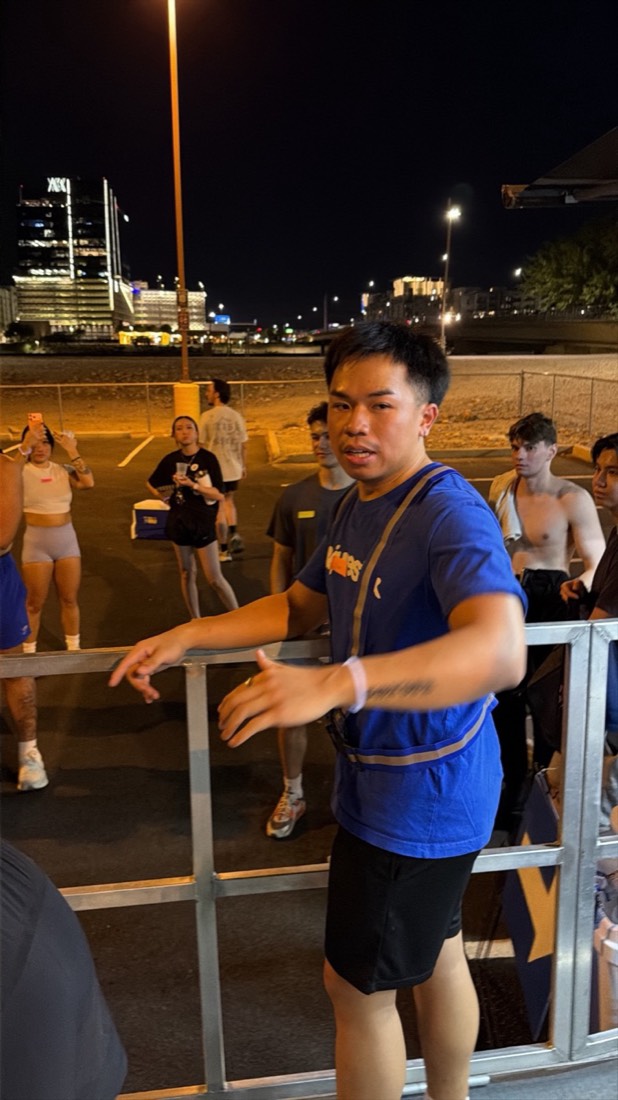 A runner in blue leaning on a rail and talking, the city lit behind him