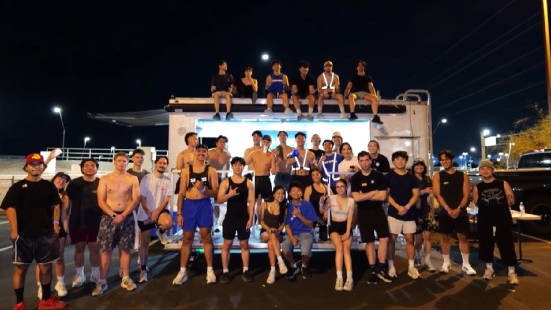 Around forty runners posing in front of the club trailer under stadium lights