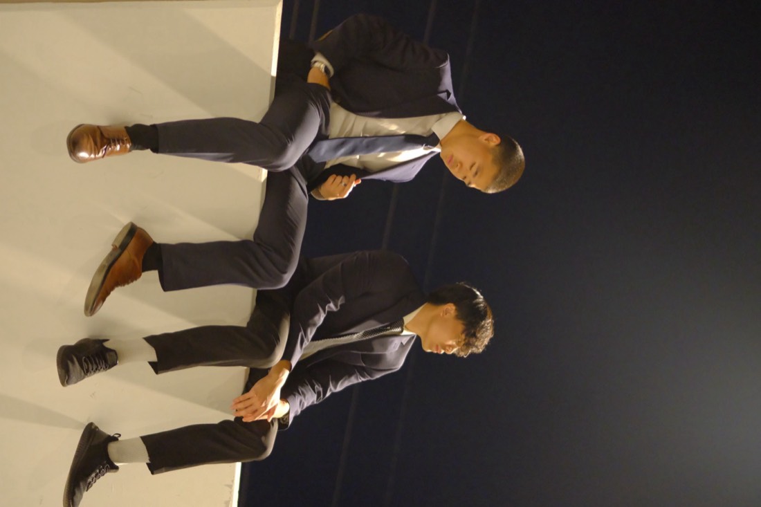 Two builders in suits sitting on a wall at night